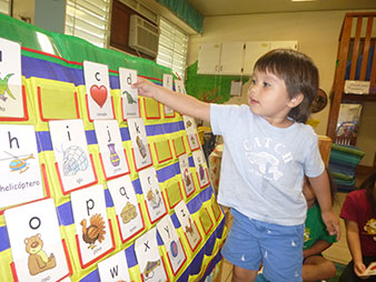 Niño seleccionando tarjeta con una letra del abecedario