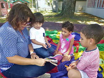 Maestra y tres niños leen en el patio